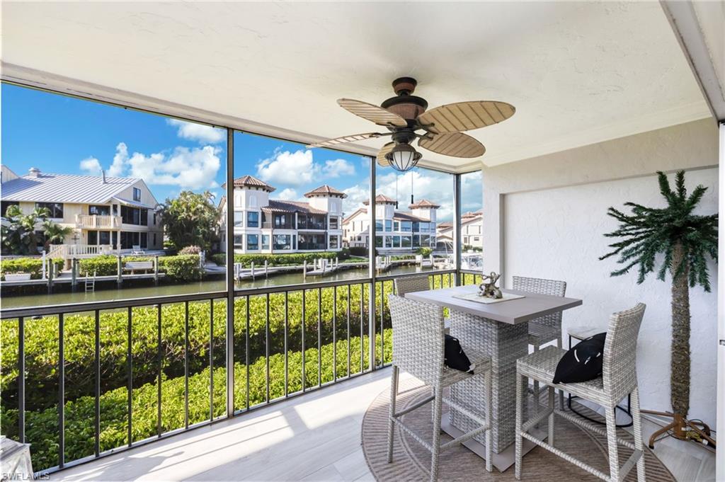 1200 Blue Point Avenue, Unit A2 Naples, FL 34102 - Photo 23 of 30 Screened-in balcony with a ceiling fan, offering views of a canal and other properties