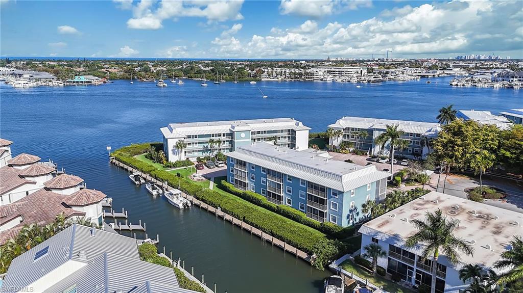 1200 Blue Point Avenue, Unit A2 Naples, FL 34102 - Photo 27 of 30 Aerial view showcasing properties situated along a canal, with a wide waterway and distant cityscape in the background