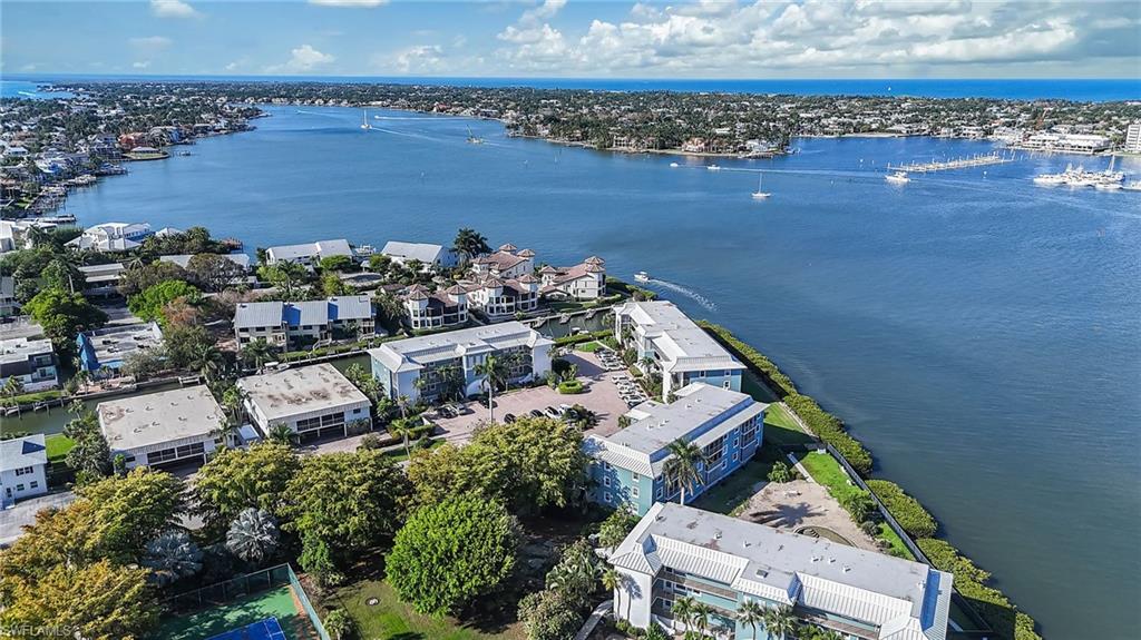 1200 Blue Point Avenue, Unit A2 Naples, FL 34102 - Photo 30 of 30 Aerial view of the property and surrounding waterway, showcasing several low-rise buildings and lush green landscaping
