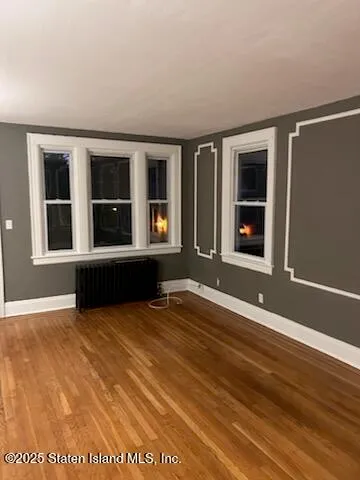 a view of an empty room with wooden floor and windows