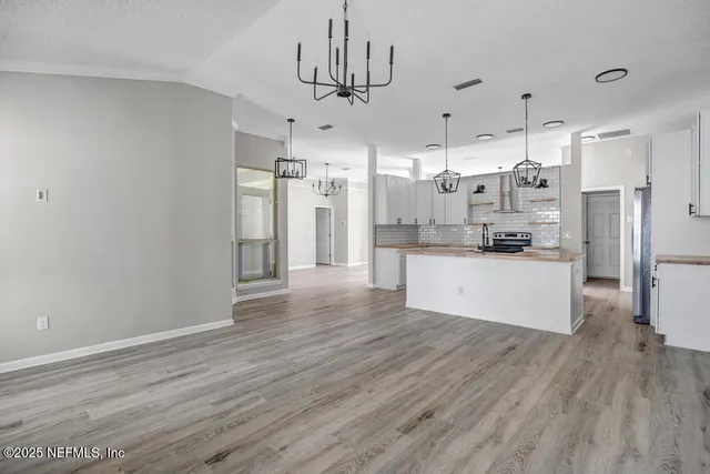 a large kitchen with stainless steel appliances a refrigerator and wooden floor