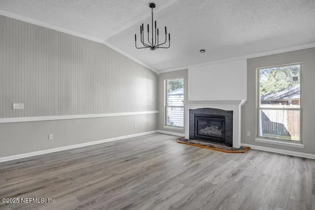 a view of an empty room with wooden floor fireplace and a window