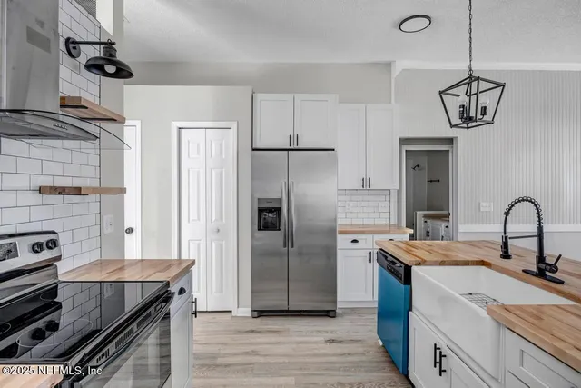 a kitchen with stainless steel appliances granite countertop a sink a stove and refrigerator