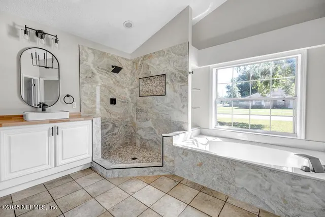 a bathroom with a granite countertop sink a mirror and a bathtub