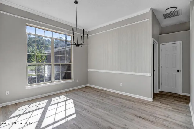 a view of an empty room with wooden floor and windows