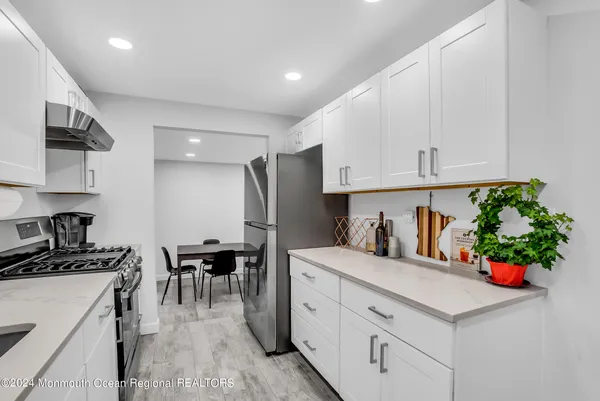 a kitchen with granite countertop a sink stainless steel appliances and white cabinets