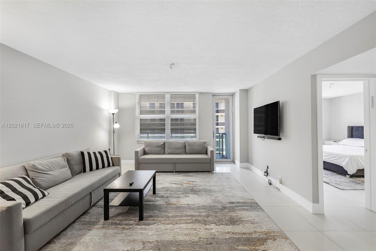 9511 Collins Avenue, Unit 1202 Surfside, FL 33154 - Photo 7 of 16 a living room with furniture and a flat screen tv