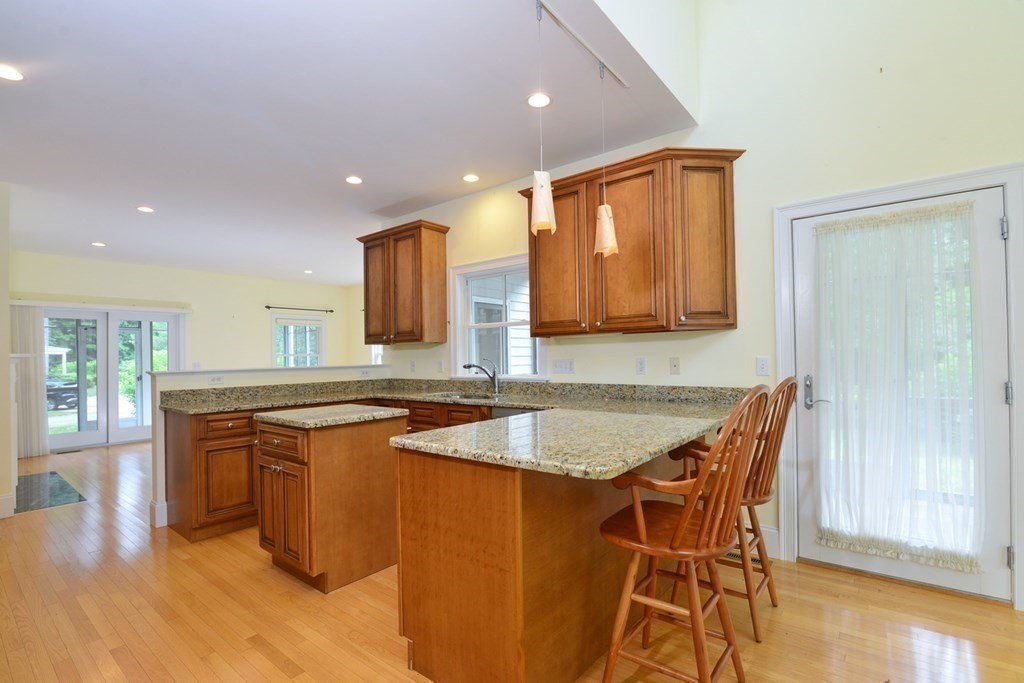 15 Hathaway Pond Circle, Unit 15 Rochester, MA 02770 - Photo 9 of 36 a kitchen with stainless steel appliances granite countertop wooden cabinets a sink a stove a dining table and chairs