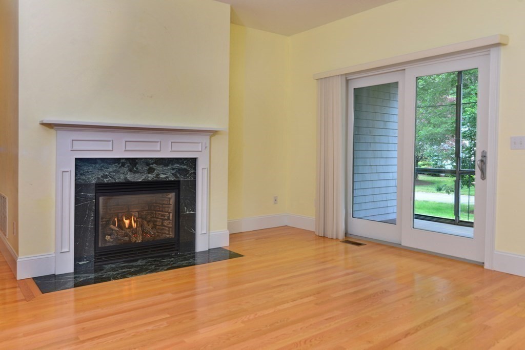 15 Hathaway Pond Circle, Unit 15 Rochester, MA 02770 - Photo 10 of 36 a view of an empty room with wooden floor fireplace and a window