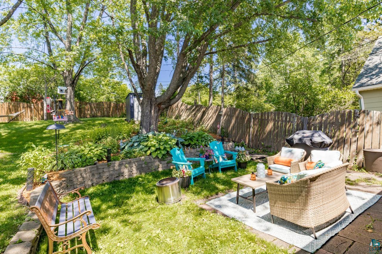 4119 Pitt Street Duluth, MN 55804 - Photo 4 of 50 Expansive backyard featuring mature trees, a wooden privacy fence, stone retaining walls, and a stone paver patio