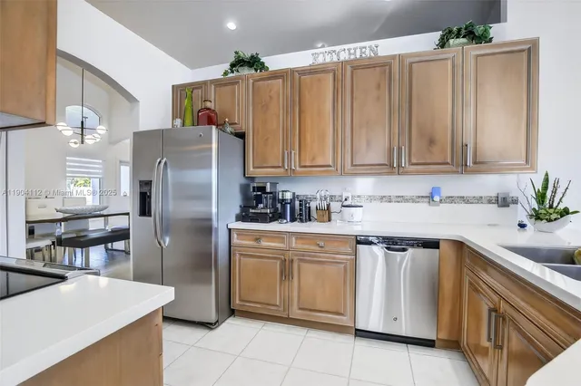 a large kitchen with kitchen island stainless steel appliances lots of table chair and a refrigerator