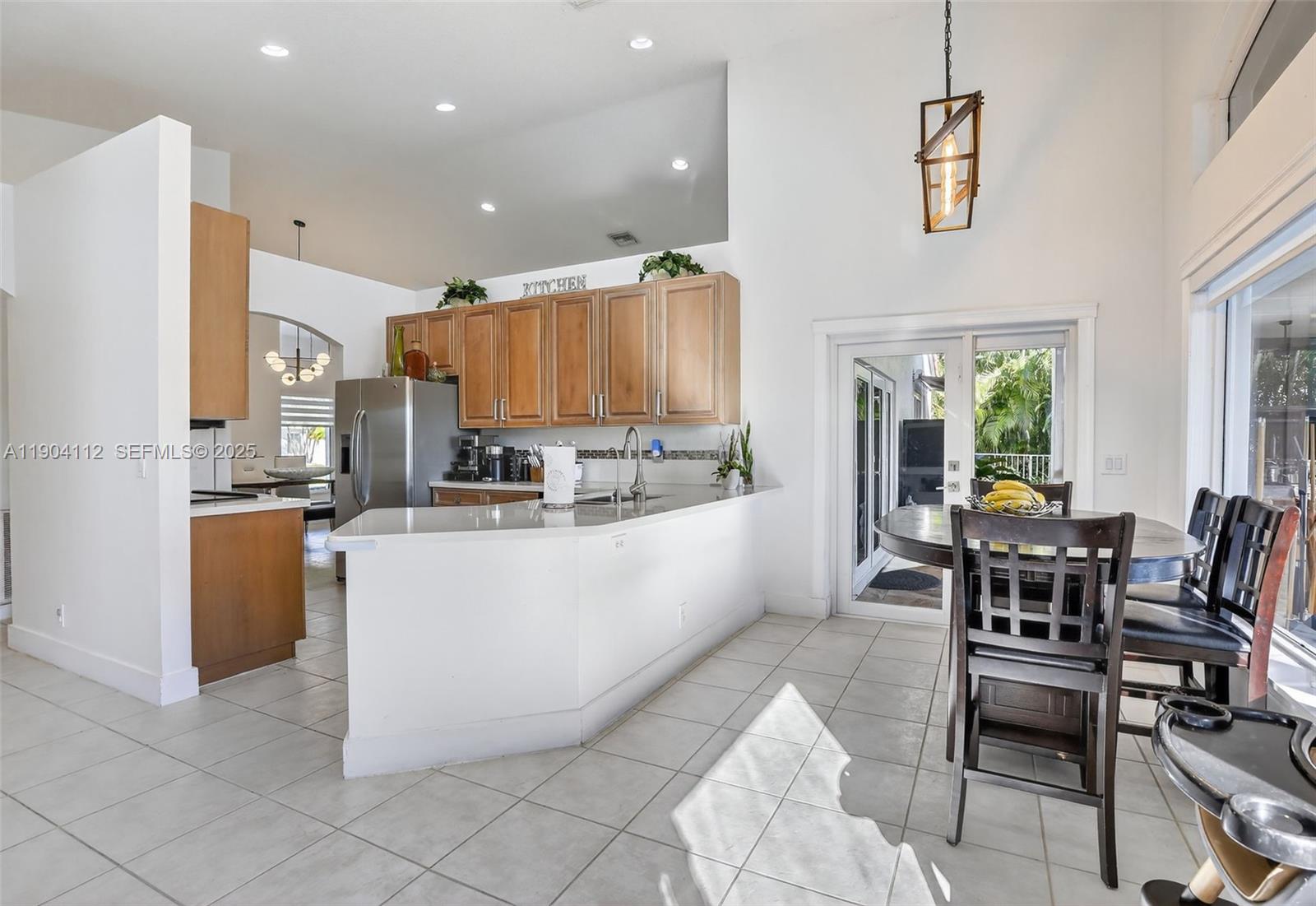 18950 Southwest 16th Street, Unit 1950 Pembroke Pines, FL 33029 - Photo 17 of 51 a large kitchen with kitchen island stainless steel appliances lots of table chair and a refrigerator