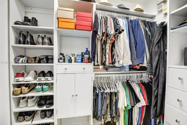 a view of walk in closet with clothes and shoes