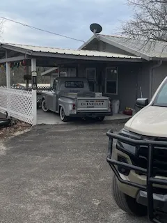 a backyard of a house with large trees and outdoor seating