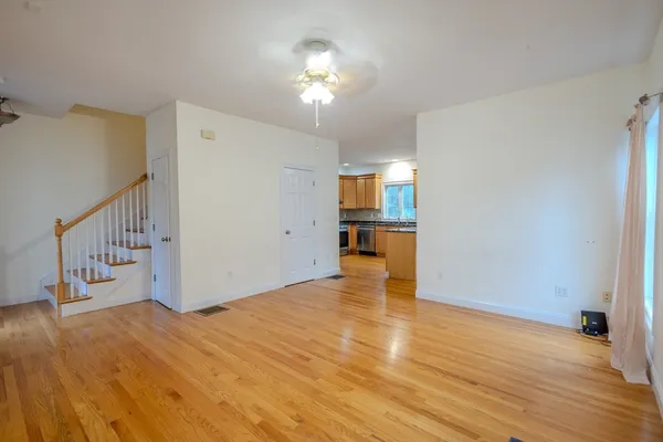 a view of an empty room with window and wooden floor