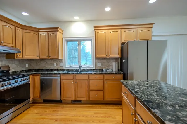 a kitchen with stainless steel appliances granite countertop a stove a sink and a refrigerator