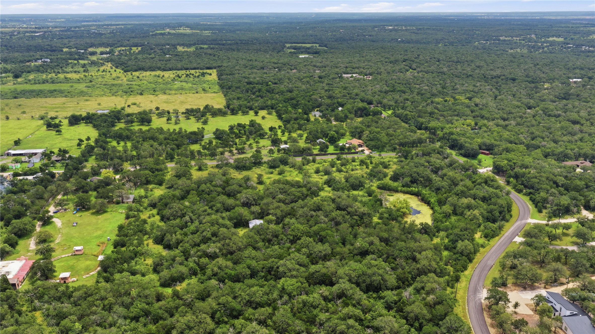 10312 Parsons Road Manor, TX 78653 - Photo 6 of 26 An aerial perspective reveals abundant tree cover, verdant open spaces, and meandering roads, painting a picture of tranquil, undeveloped land.