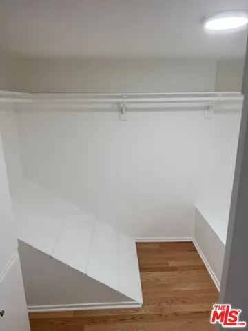 a view of walk in closet with wooden floor