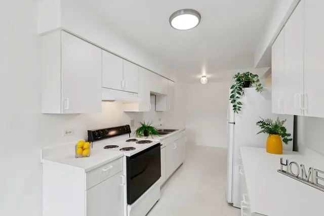 a kitchen with a sink a stove cabinets and wooden floor