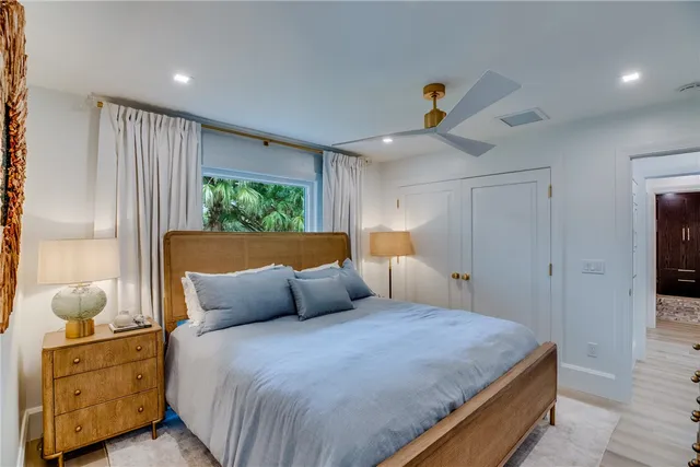 a bedroom with a bed a window and potted plant on the dresser
