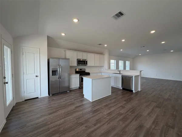 a large kitchen with a lot of counter space stainless steel appliances and wooden floor
