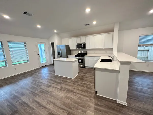 a kitchen with kitchen island a sink a stove and a refrigerator