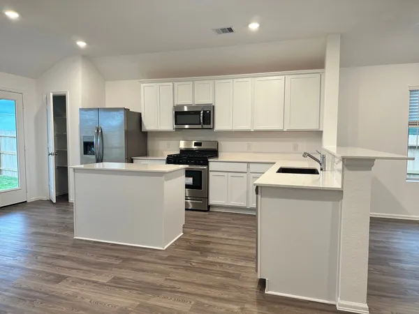a kitchen with a refrigerator a sink and dishwasher with wooden floor