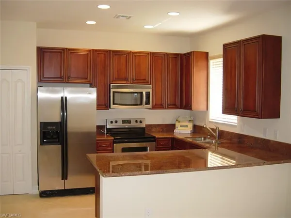 a kitchen with stainless steel appliances granite countertop a sink a stove and a refrigerator with wooden floor