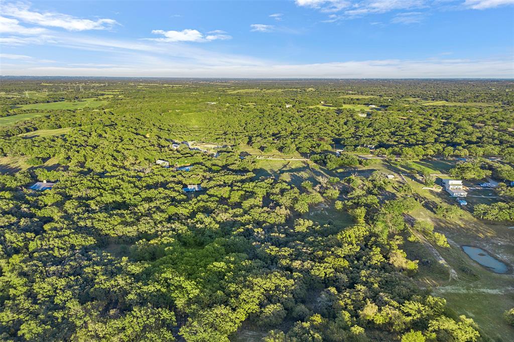 199 Cheyenne Trail Springtown, TX 76082 - Photo 17 of 22 Expansive acreage featuring dense tree cover, multiple structures, and a natural pond