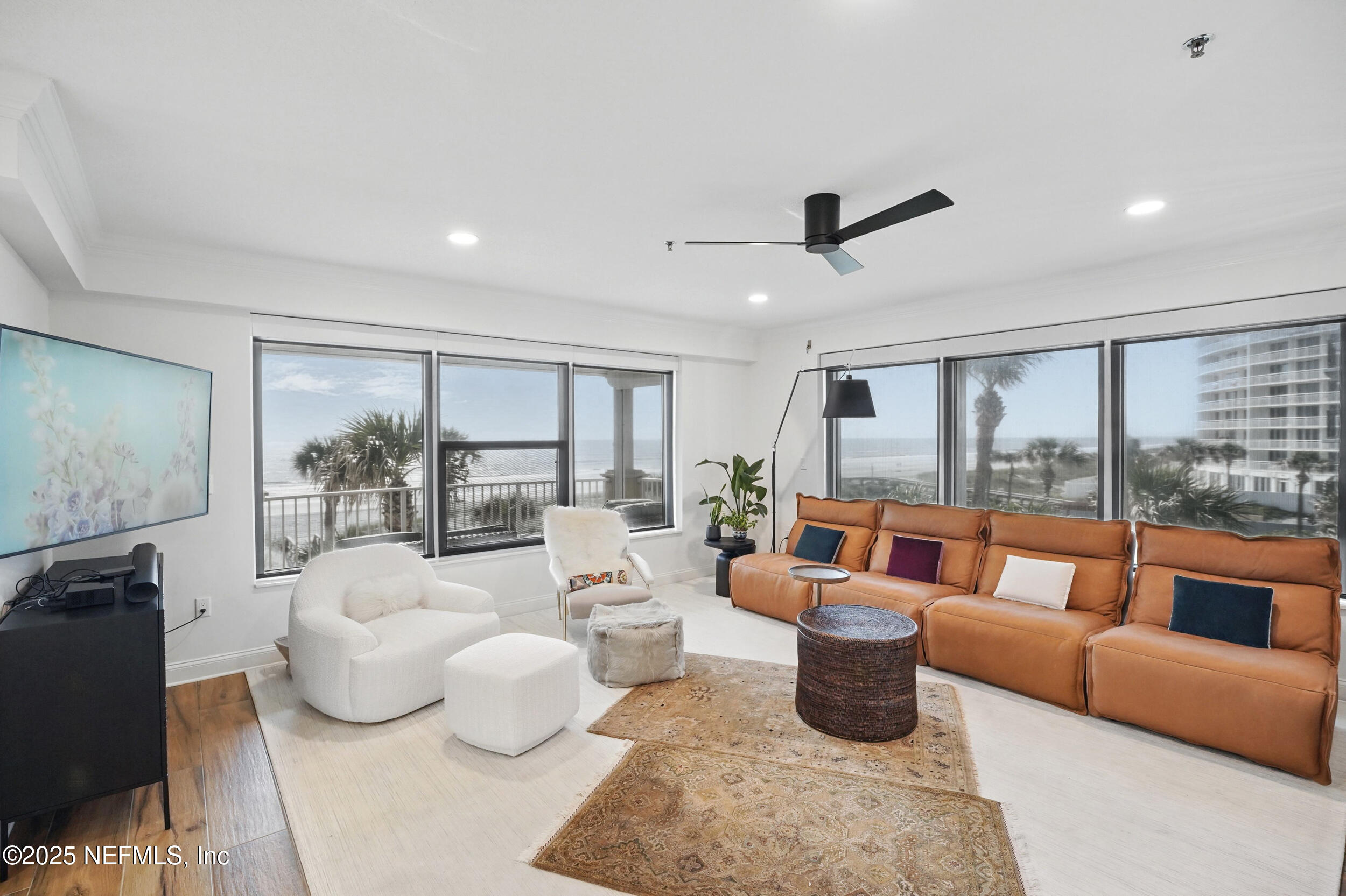1505 1st Street South, Unit 302 Jacksonville Beach, FL 32250 - Photo 23 of 57 a living room with furniture large windows and a flat screen tv