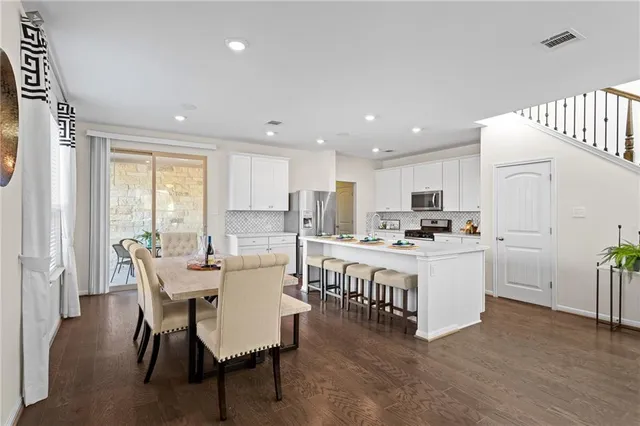 a kitchen with a dining table chairs and white appliances