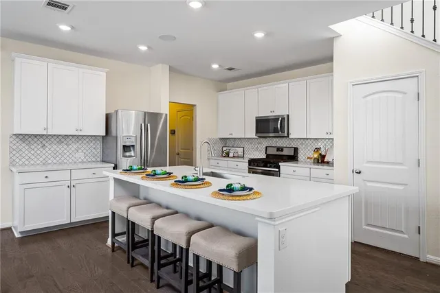 a kitchen that has a lot of cabinets a sink and appliances