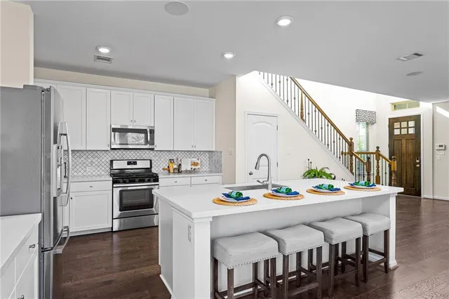 a kitchen with stainless steel appliances kitchen island granite countertop a kitchen island and chairs in it