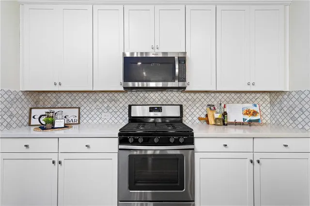 a kitchen with granite countertop white cabinets and stainless steel appliances