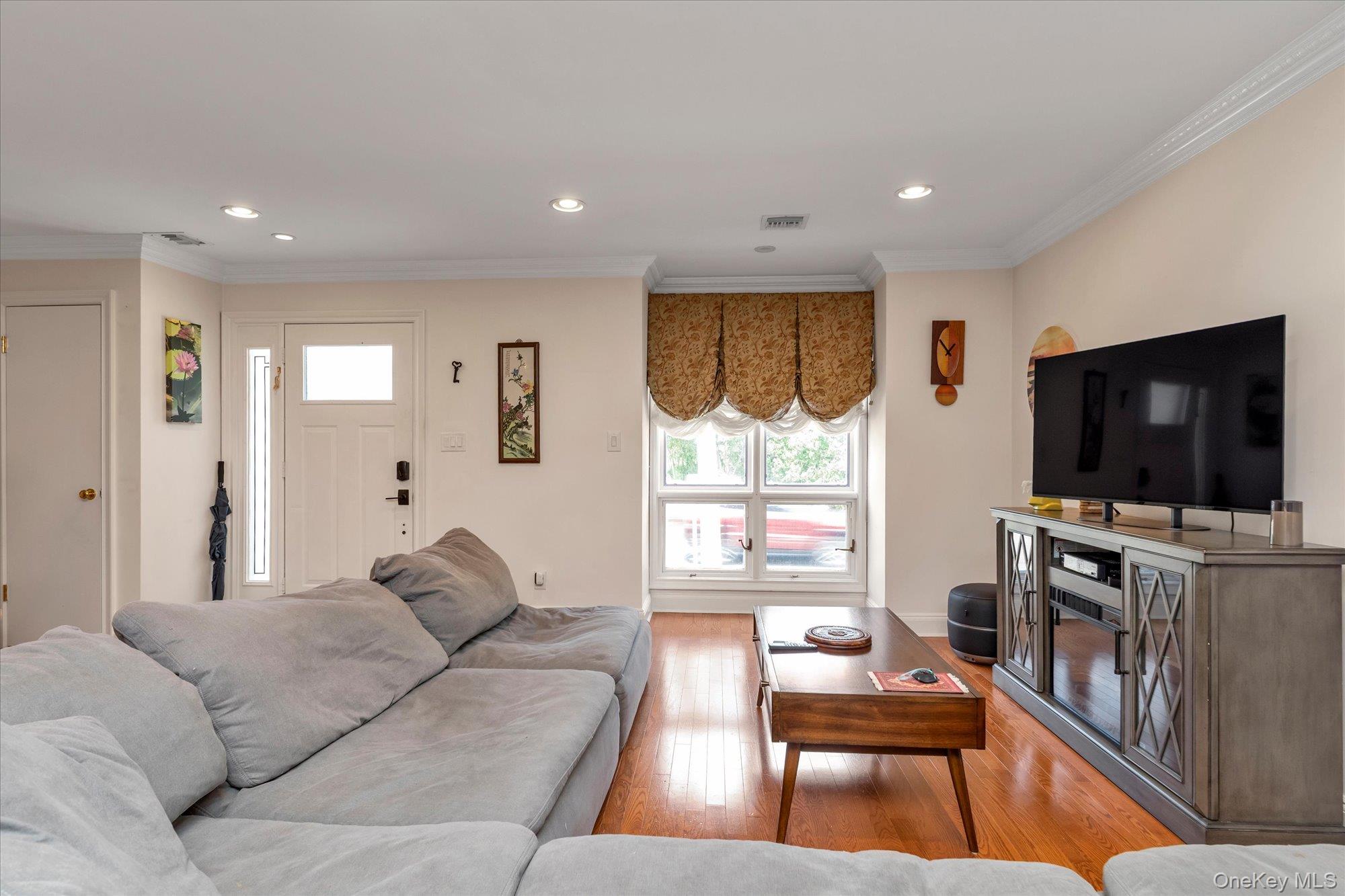 150 I U Willets Road Albertson, NY 11507 - Photo 4 of 21 Sunny living room featuring wood-finish flooring, and a window with patterned Roman shades