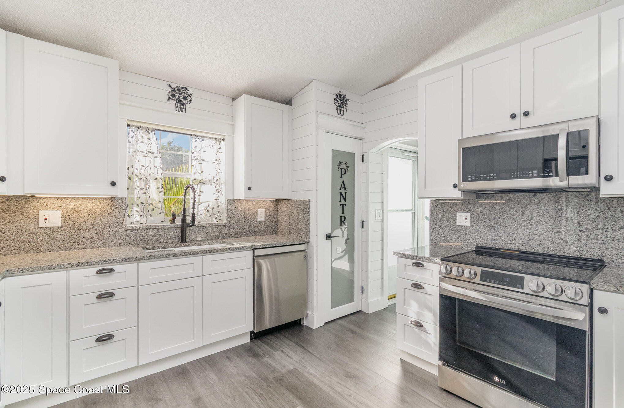 561 Carnival Terrace Sebastian, FL 32958 - Photo 6 of 28 a kitchen with stainless steel appliances granite countertop a stove a sink and a microwave
