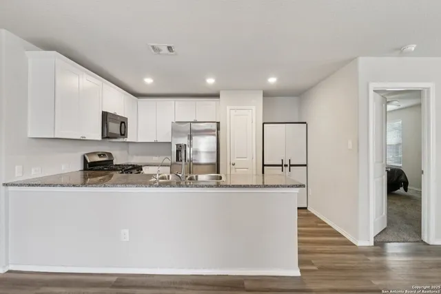 a kitchen with stainless steel appliances granite countertop a sink a stove a refrigerator a microwave and cabinets