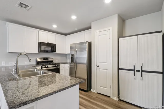 a kitchen with a refrigerator a microwave a sink and cabinets