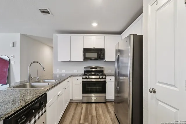 a kitchen with stainless steel appliances granite countertop a stove microwave and sink