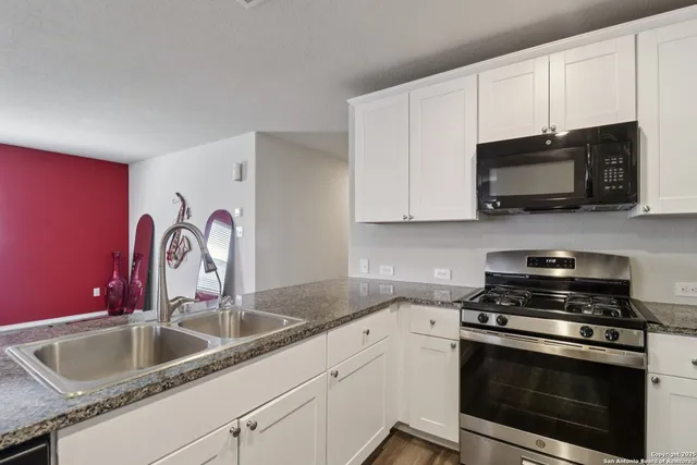 a kitchen with granite countertop a sink stainless steel appliances and cabinets