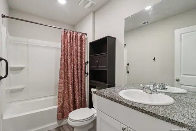 a bathroom with a granite countertop sink toilet and shower