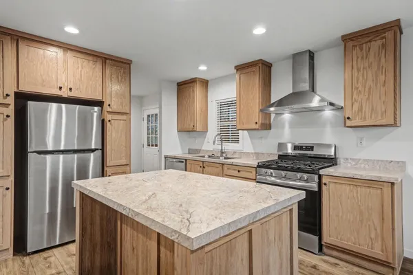 a kitchen with stainless steel appliances granite countertop a stove a refrigerator and a sink