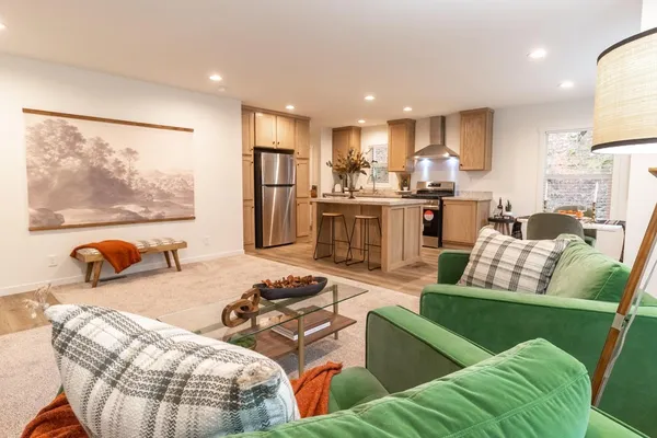 a living room with furniture kitchen view and a large window