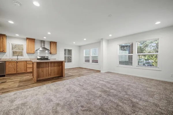 a view of kitchen with kitchen island granite countertop stainless steel appliances stove sink and cabinets