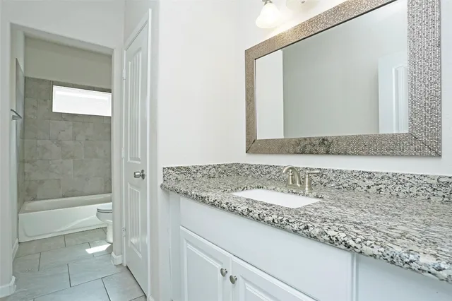 a bathroom with a granite countertop sink and a mirror