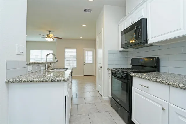 a kitchen with granite countertop a sink and a stove top oven with wooden floor