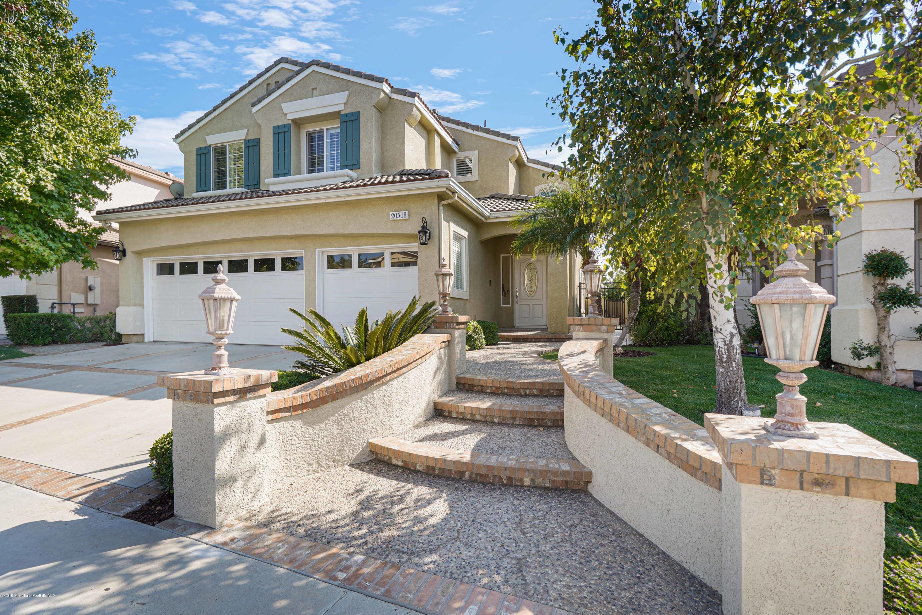 20548 Bergamo Way Porter Ranch, CA 91326 - Photo 2 of 58 a front view of a house with a garden and trees