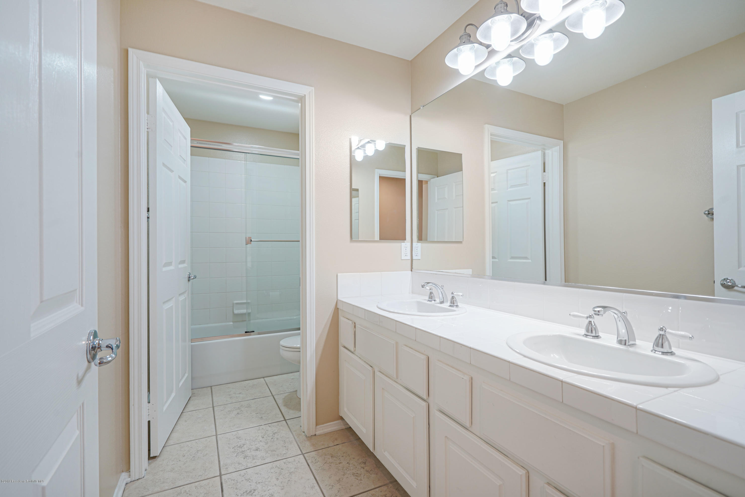 20548 Bergamo Way Porter Ranch, CA 91326 - Photo 31 of 58 a spacious bathroom with a granite countertop sink a mirror and a shower