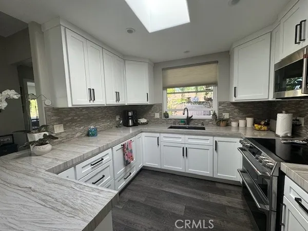 a kitchen with stainless steel appliances granite countertop a stove a sink and a white cabinets