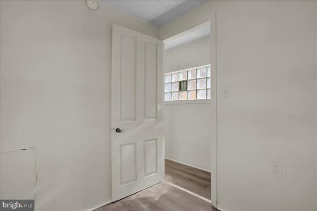 a view of an empty room with wooden floor and closet